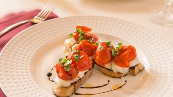 A plate of bruschetta with tomatoes and greens on a white plate.