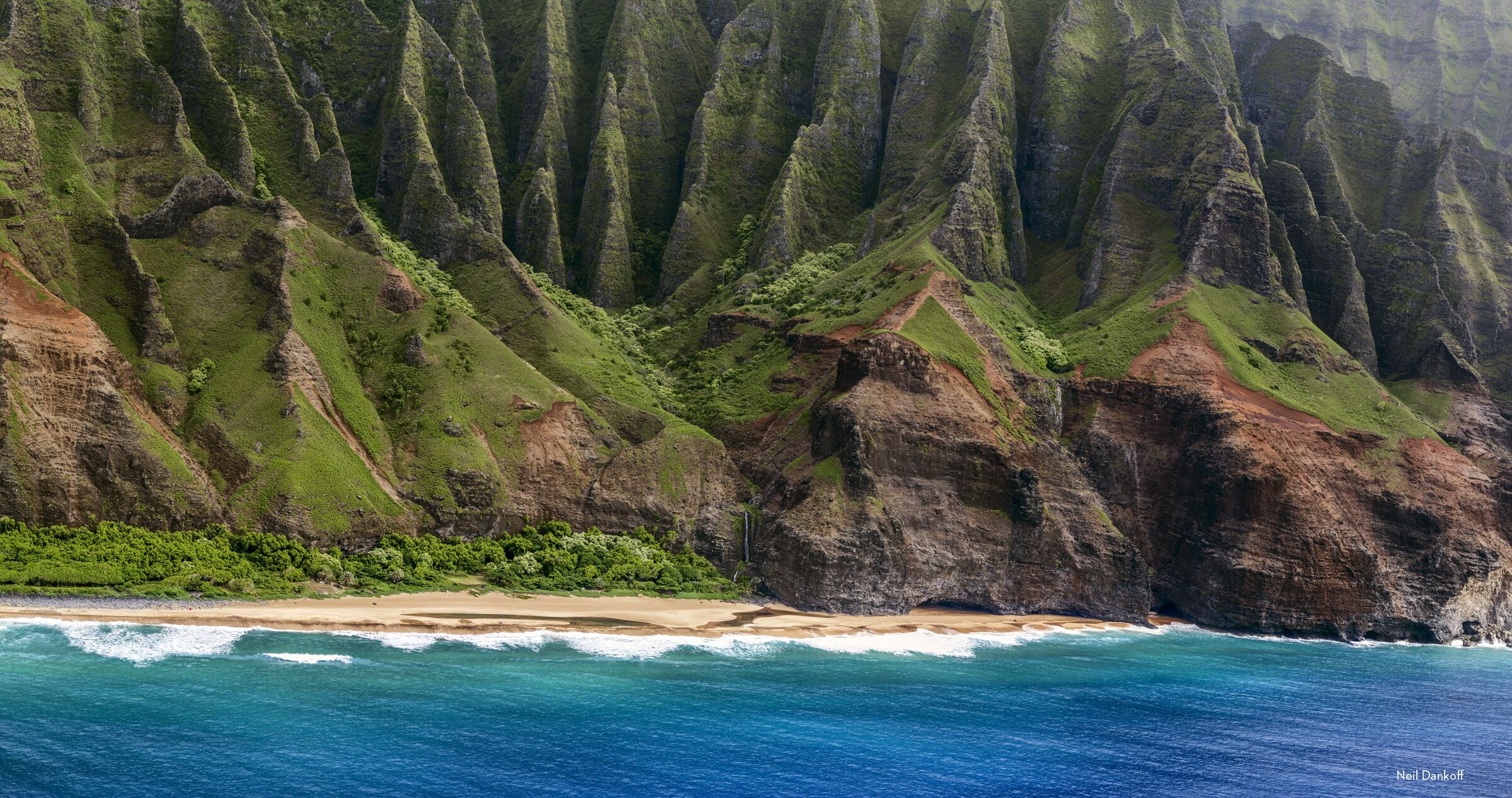 Un paysage côtier caractérisé par de hautes falaises, une plage et des vagues déferlantes.