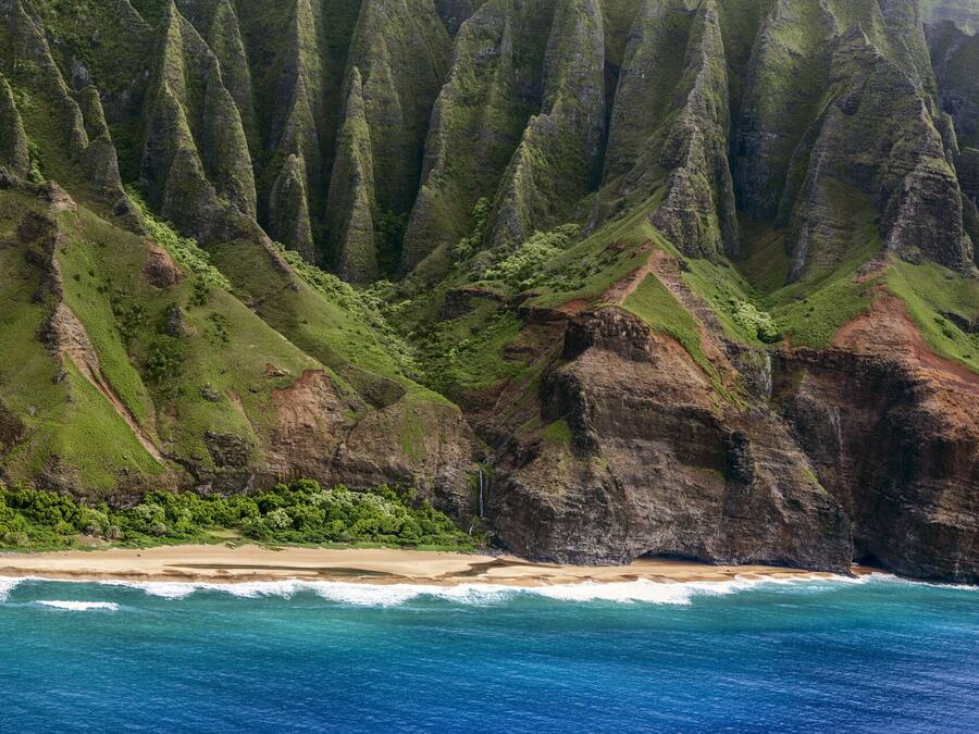 A coastal landscape with steep cliffs, a beach, and ocean waves.