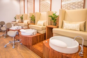 A modern spa room with multiple seating areas, a large bathtub, and a sink.