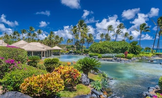 Um resort tropical com piscina, palmeiras e construções com telhado de palha.