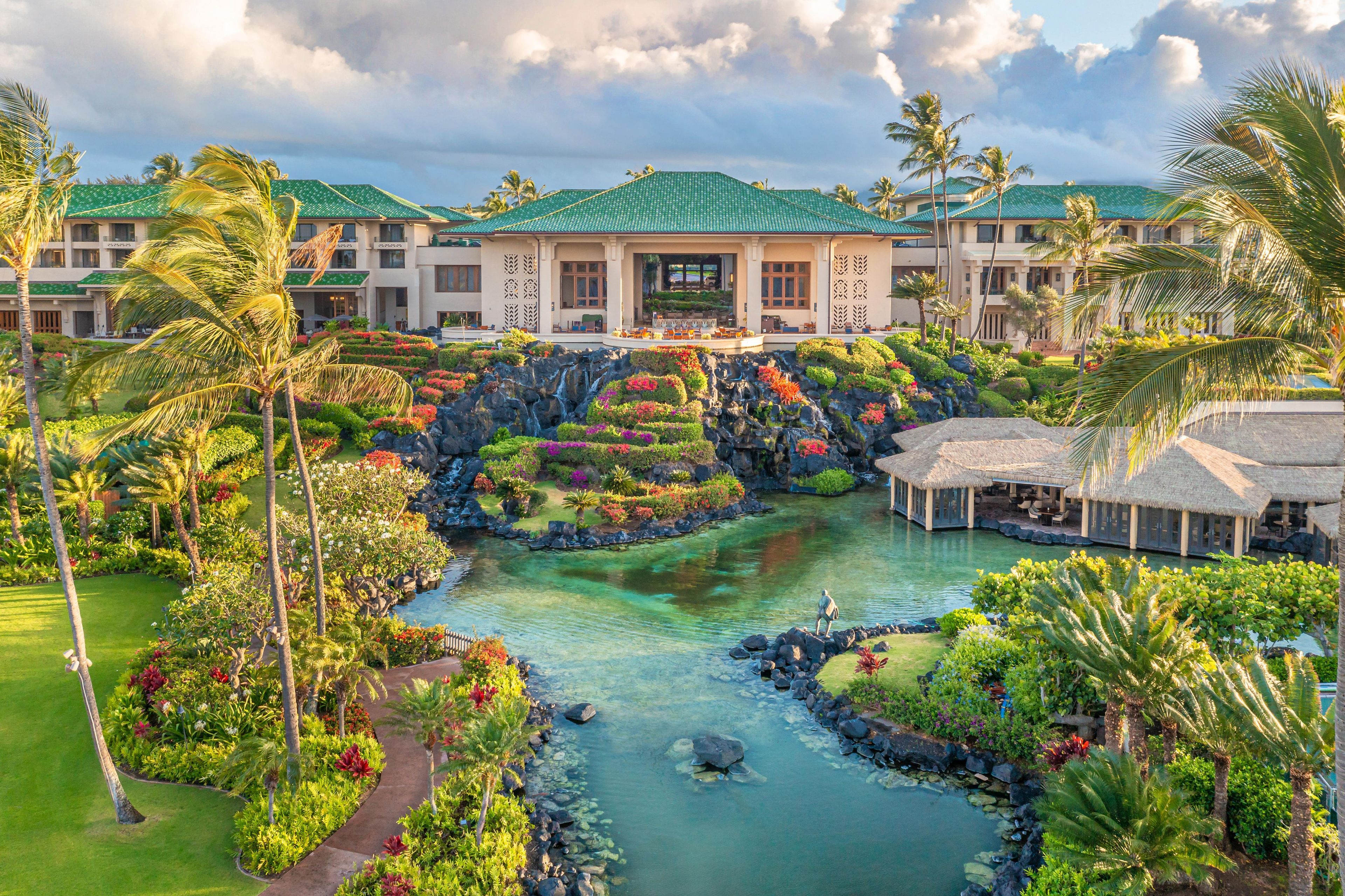 Un resort con una fuente central, abundante vegetación y un edificio con techo verde.