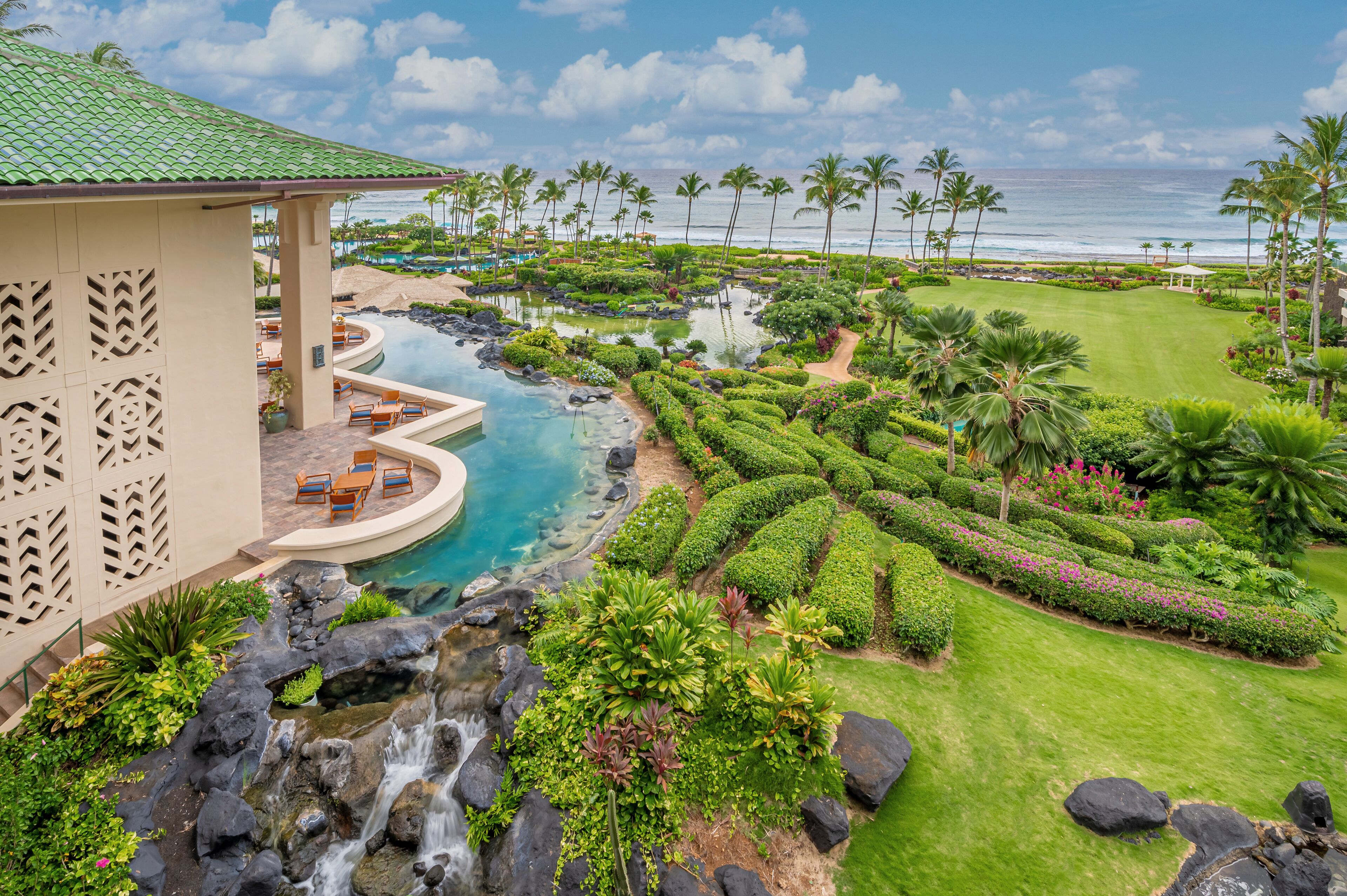 Ein Resort mit Pool, Palmen und Blick auf den Ozean.