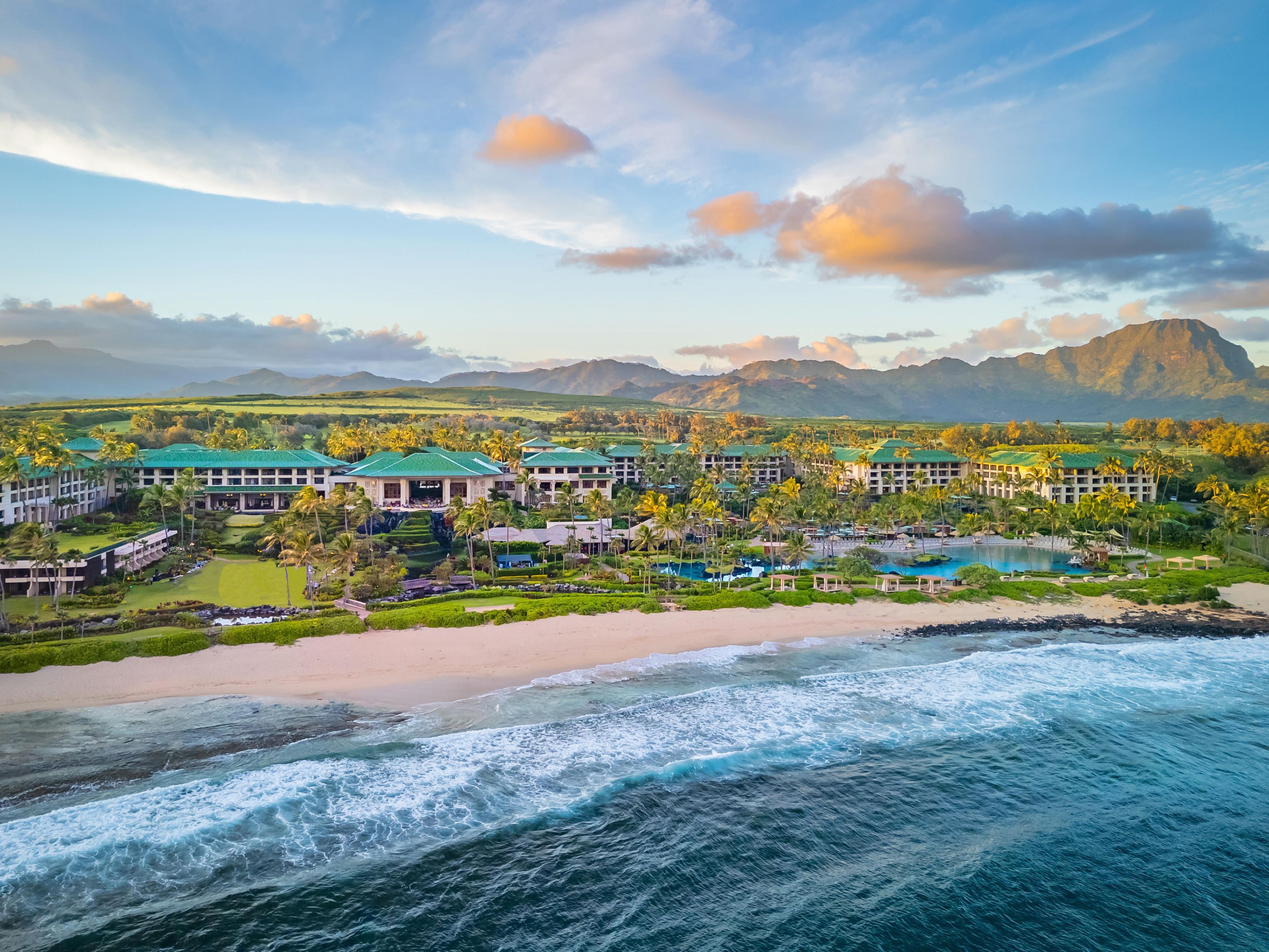 A resort with multiple buildings, a beach, and a mountain in the background.