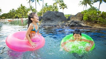 Guests can enjoy a leisurely float in the resort's tranquil waters, surrounded by lush palm trees and scenic rocks.
