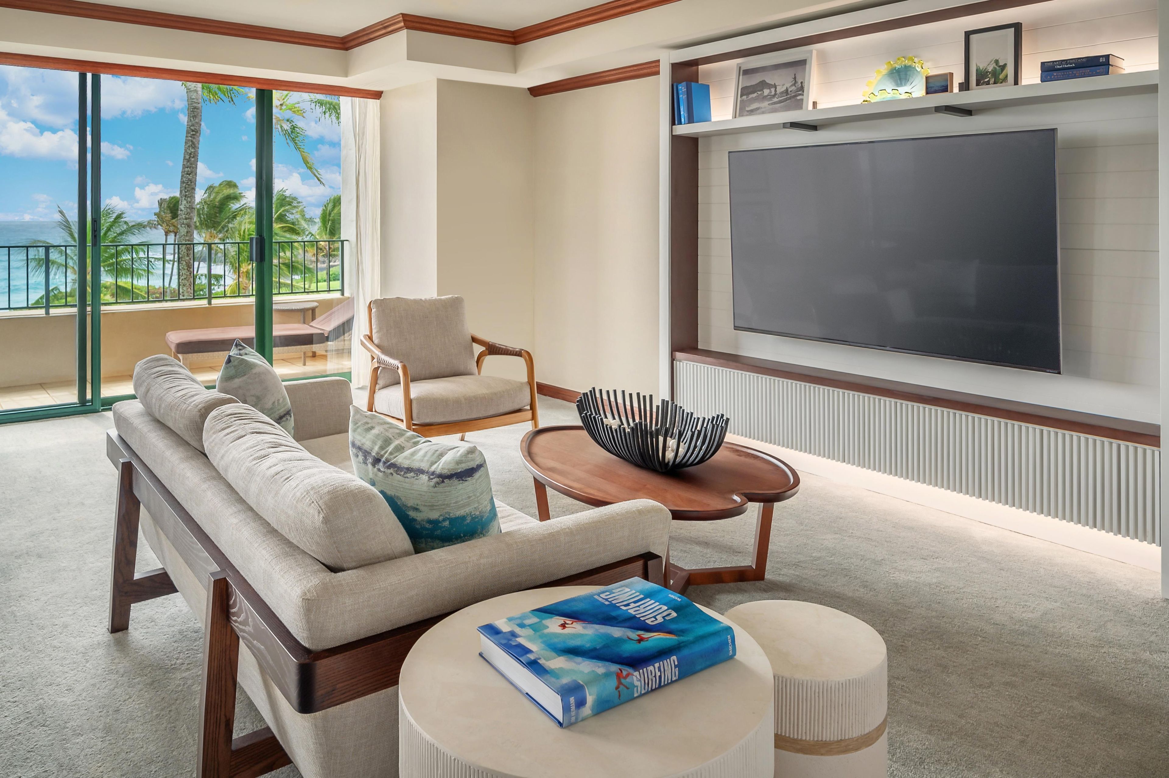 A hotel room with a balcony, a sofa, a chair, a coffee table, and a TV.