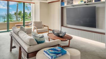 A hotel room with a balcony, a sofa, a chair, a coffee table, and a TV.