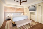 A hotel room with a bed, bedside tables, a television, and a wardrobe.