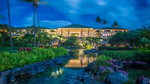 Un complexe hôtelier doté d’un grand bâtiment, d’un étang et d’un aménagement paysager de style tropical.