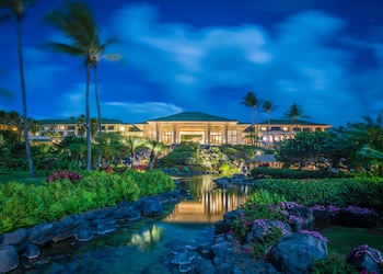 A golf course with a view of the ocean and palm trees. at Grand Hyatt Kauai Resort and Spa
