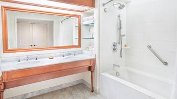 A bathroom with a wooden vanity, a large mirror, a bathtub, and a shower area.