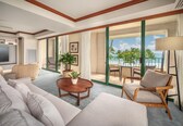 A hotel room with a balcony, a television, a sofa, a coffee table, and a potted plant.