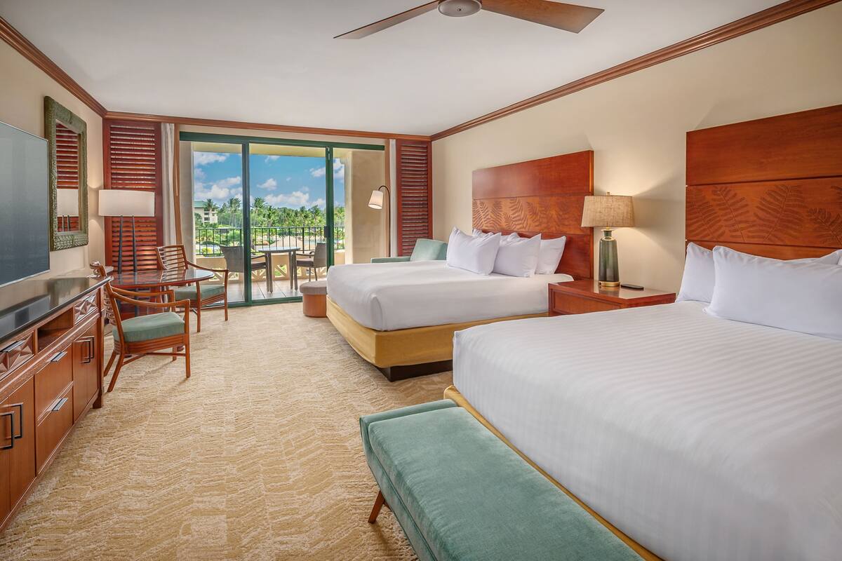 Une chambre d’hôtel avec deux lits, un bureau avec une chaise, une télévision et un balcon avec vue.