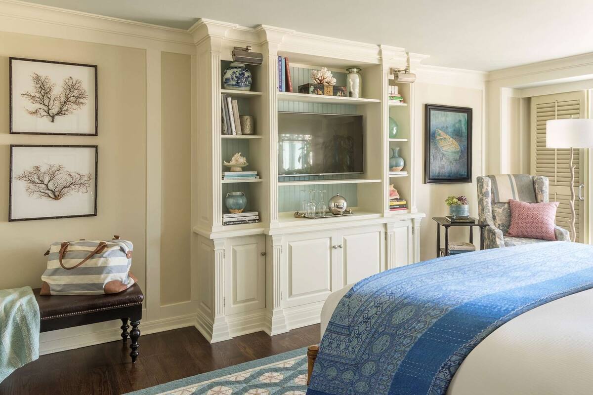 A bedroom with a large bed, a built-in bookshelf, a small table, and a chair.