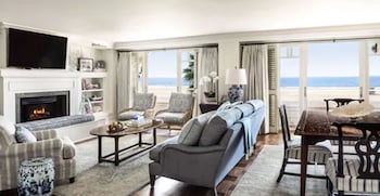 A bedroom with a bed, a fireplace, a TV, and a view of the ocean. at Shutters on the Beach