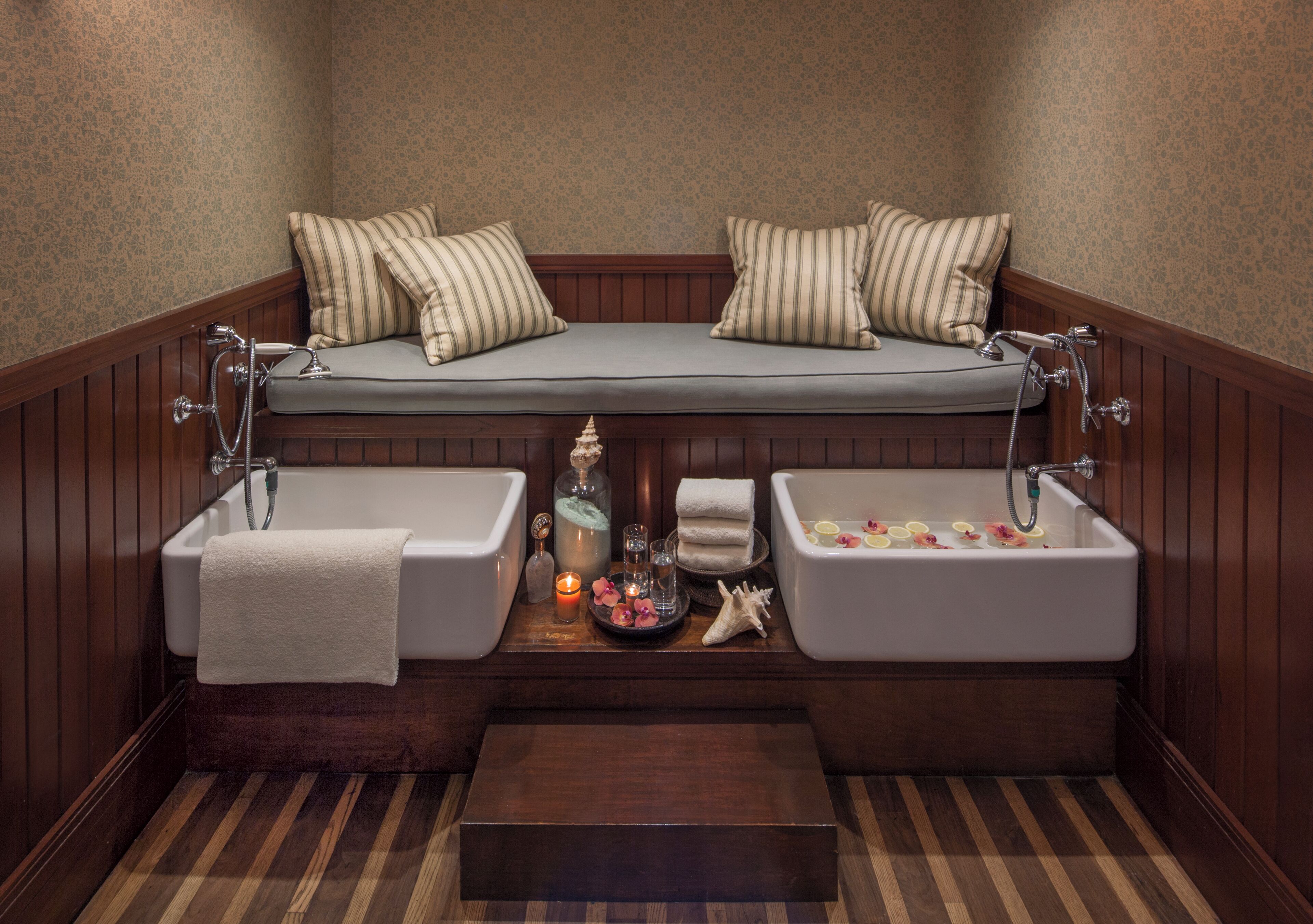 A bathroom with a wooden bench, two sinks, and a bathtub.