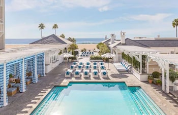 A spacious living room with a fireplace, comfortable seating, a coffee table, and large windows offering a view of the beach. at Shutters on the Beach