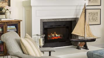 A living room with a fireplace, a sailboat decoration, and a patterned rug.