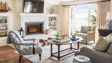 A cozy living room with a fireplace, a sofa, a striped armchair, and a coffee table.
