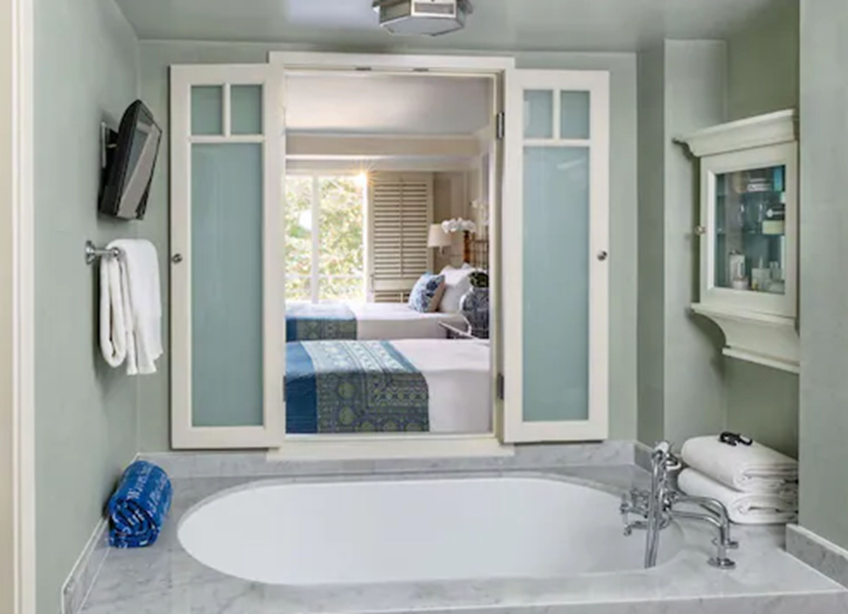 Een badkamer met een ruime badkuip, douche en toilet. Handdoekhouder met handdoeken en een blauwe handdoek op de vloer.