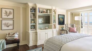 A bedroom with a large bed, a built-in bookshelf, a chair with a view, and artwork on the walls.