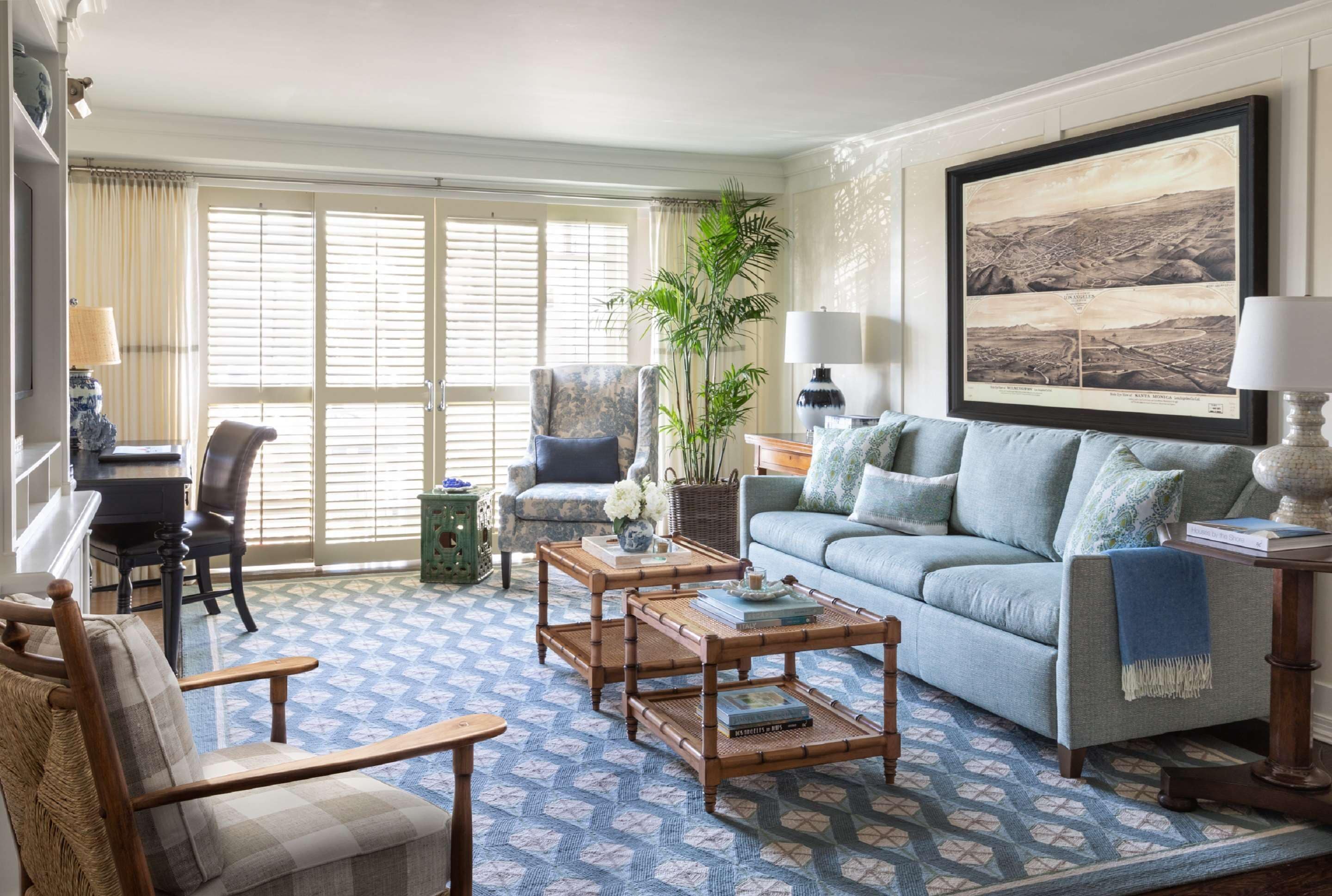 A living room with a patterned carpet, a blue sofa, a wooden coffee table, and a large framed map on the wall.