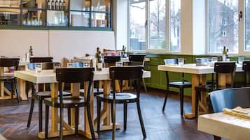 A restaurant interior with wooden flooring, tables, chairs, and a wine display.
