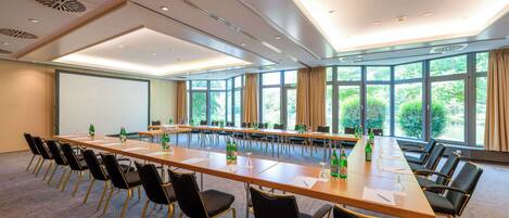 A conference room with a long table, chairs, and a projector screen.