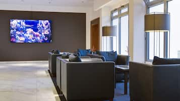Eine moderne Lobby mit einem großen Flachbildfernseher, bequemen Sitzgelegenheiten und großen Fenstern.