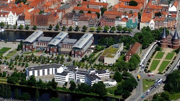 Eine Vogelperspektive auf eine Stadt mit einer Mischung aus historischen und modernen Gebäuden, einem Fluss und einem großen Grünanlagengebiet.