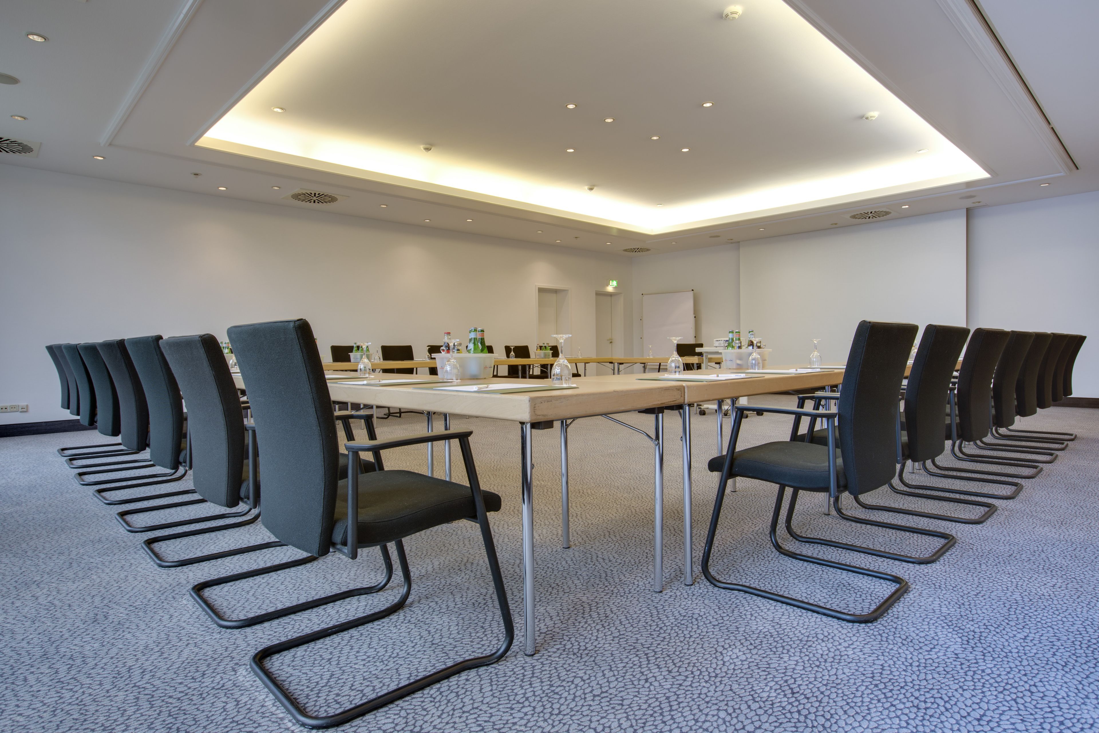 Une salle de conférence avec une longue table, de nombreuses chaises et un tableau blanc.