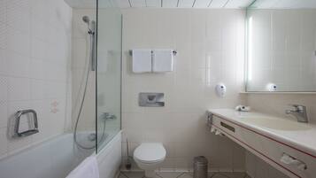 Ein modernes Badezimmer mit Duschkabine aus Glas, Toilette, Waschbecken mit Spiegel und Mülleimer.