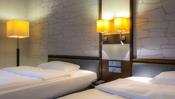 A hotel room with two beds, a stone-patterned wall, and two wall-mounted lamps.
