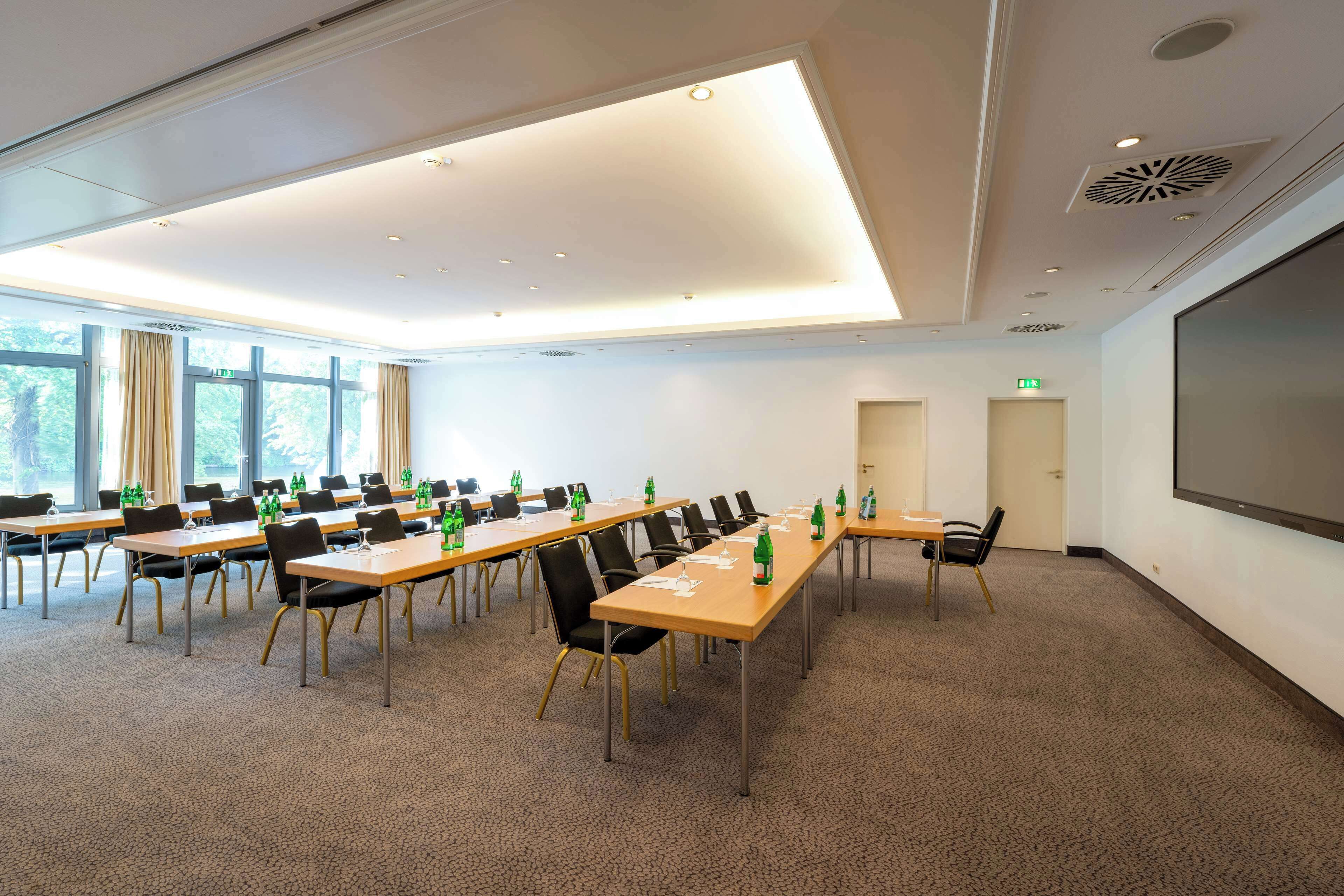Ein Konferenzraum mit mehreren Tischen, Stühlen und einer großen Leinwand.