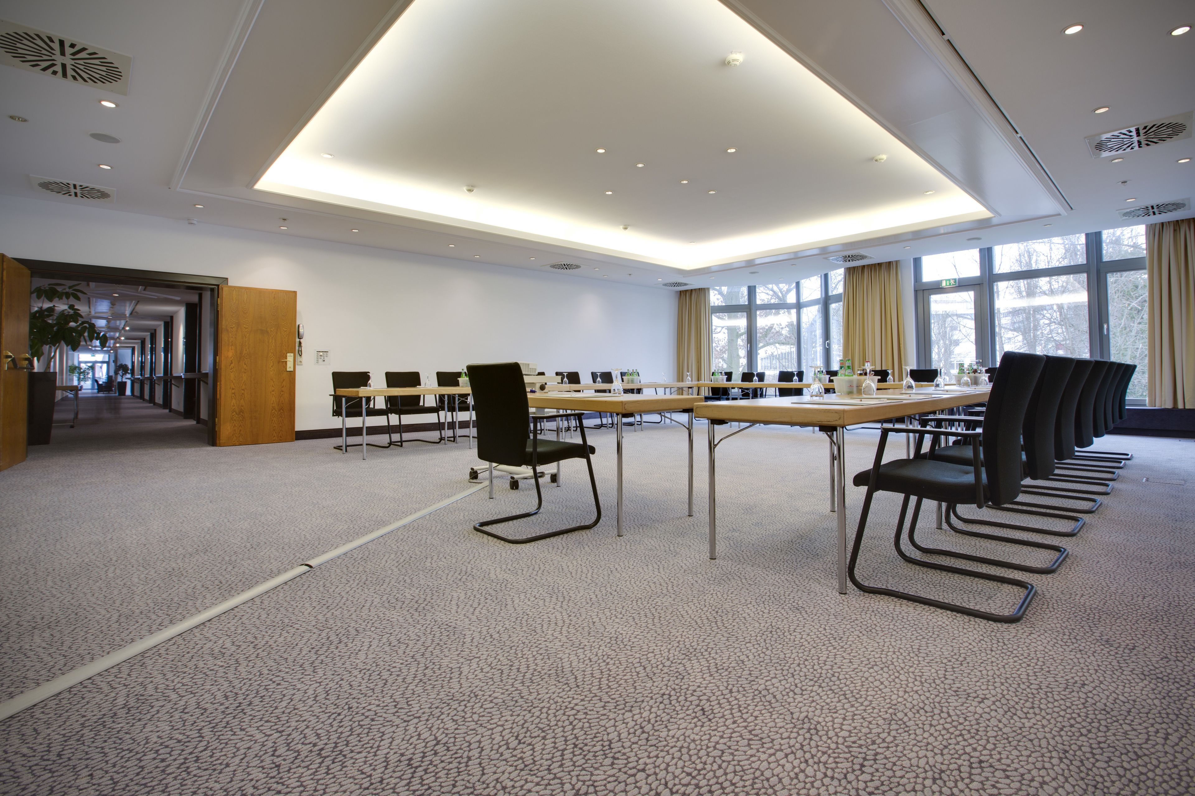 A conference room with a long table, chairs, and a carpeted floor.