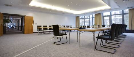 A conference room with a long table, chairs, and a carpeted floor.