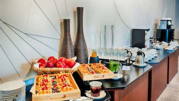 A buffet with waffles, fruits, and beverages.