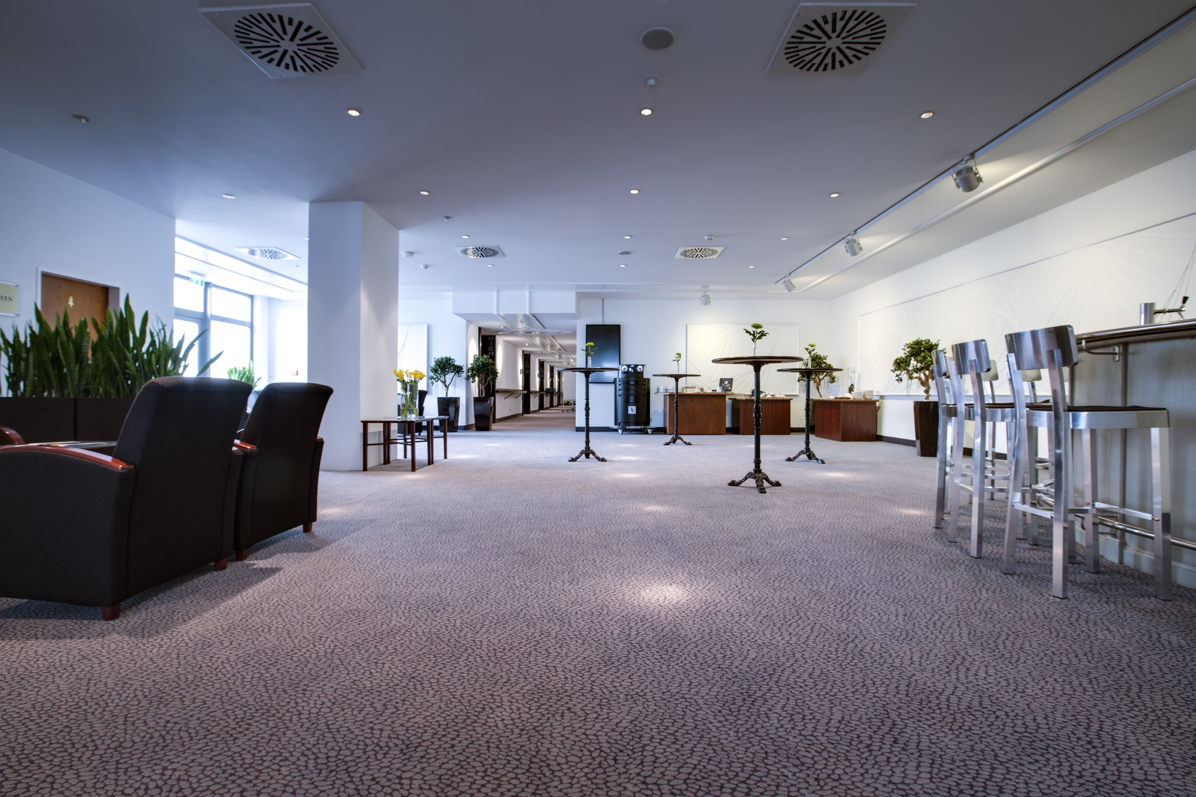 A spacious lobby with a high ceiling, modern furniture, and a mix of seating areas.