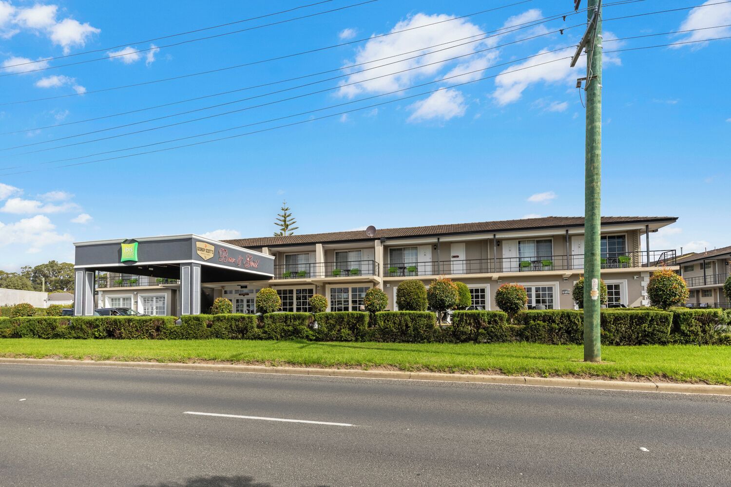 A hotel with a two-story structure, a covered outdoor area, and a well-maintained lawn.