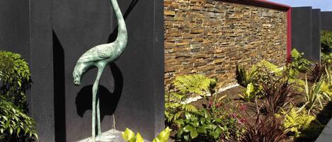 A bronze sculpture of a bird, possibly a crane, mounted on a black wall.