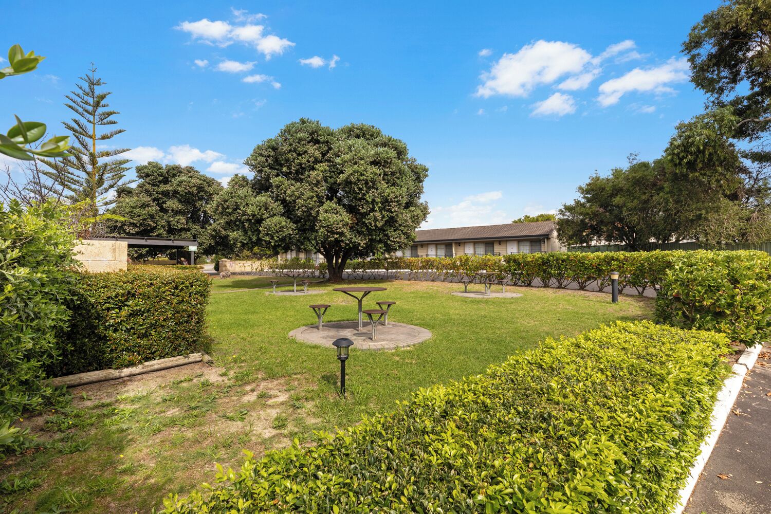 A well-maintained courtyard with a large tree, several tables, and benches.