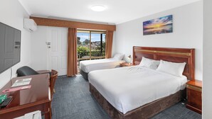 A hotel room with two beds, a desk, a chair, a TV, and a balcony with a view. - ibis Styles Albany (Orana)