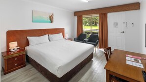 A hotel room with a large bed, a desk, two chairs, a TV, and a window with curtains. - ibis Styles Albany (Orana)