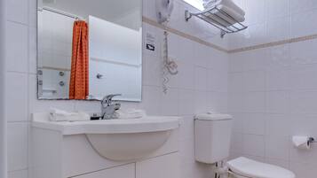 A bathroom with a white sink, mirror, and toilet.
