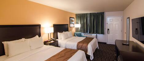 A hotel room with two beds, a desk, a chair, a TV, and a door.