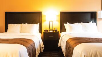 A hotel room with two beds, a nightstand with a lamp, and a carpeted floor.