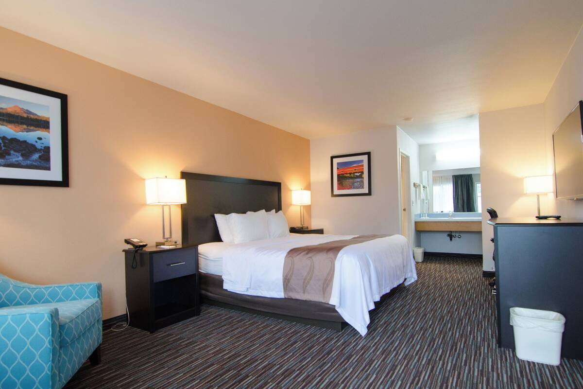 A hotel room with a bed, bedside tables, a desk, and a chair.