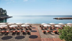 A beachside area with rows of sun loungers and umbrellas, a wooden walkway, and a calm sea. - Le Meridien Beach Plaza (Monaco)