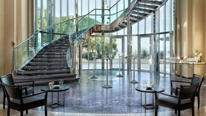 A spacious lobby with a glass staircase, modern furniture, and a view of the outdoors. - Le Meridien Beach Plaza (Monaco)