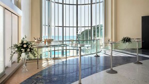 A spacious lobby with a glass railing, a view of a pool, and a reception desk. - Le Meridien Beach Plaza (Monaco)